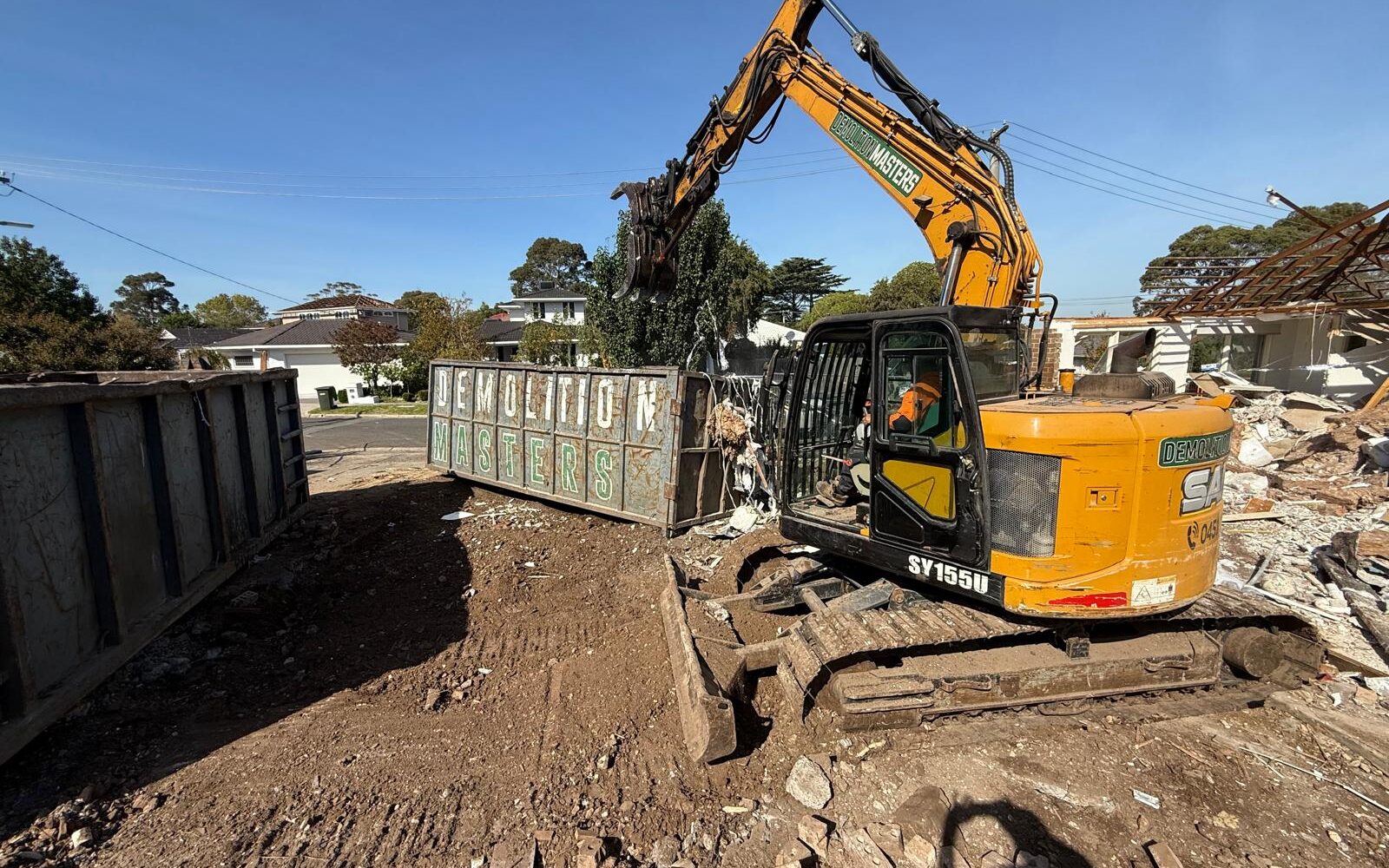 Large Demolition Masters branded bin positioned on a Melbourne demolition site alongside an excavator