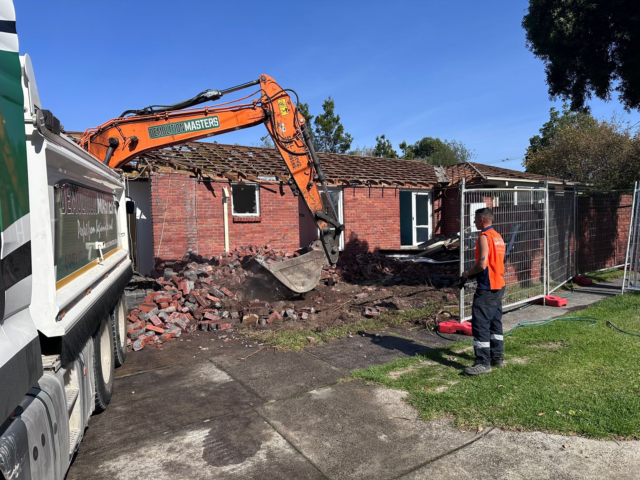 Branded Demolition Masters orange excavator on a residential demolition site in Melbourne