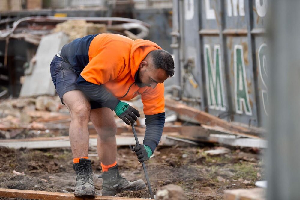 Demolition Masters crew member working beside a branded bin on a Melbourne site
