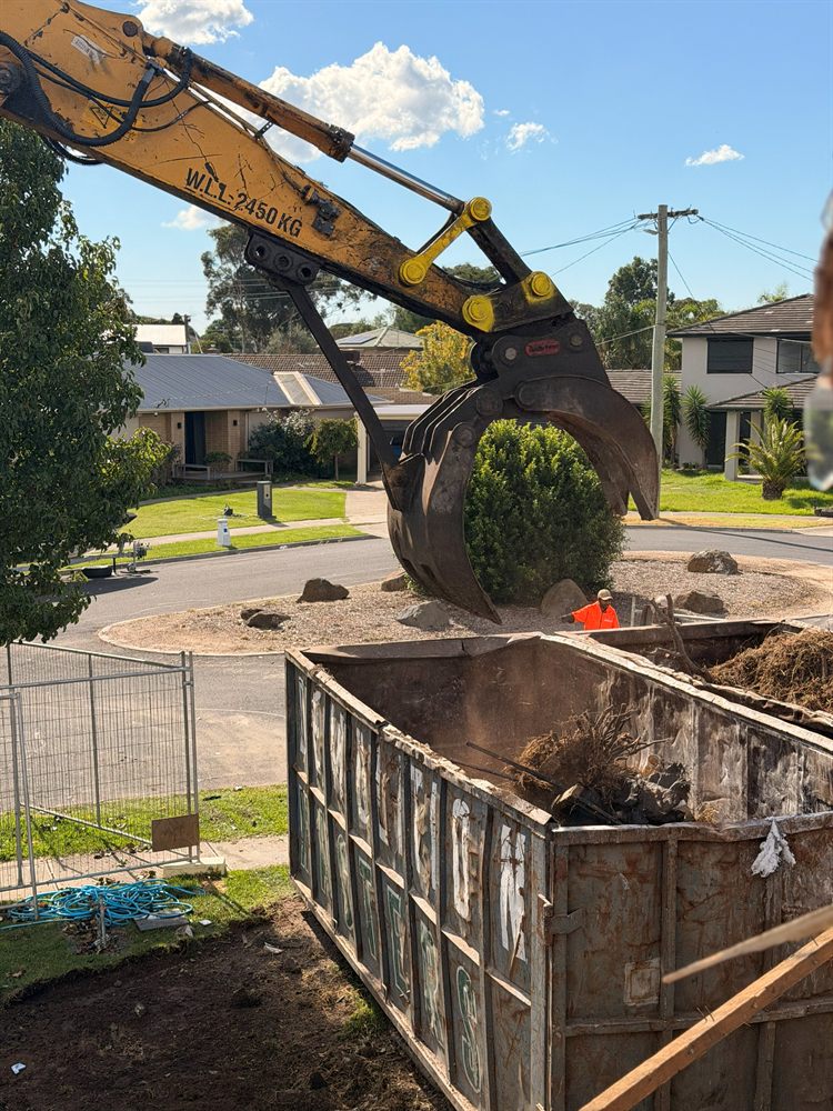 Excavator grab positioned over a Demolition Masters bin during a site clean-up