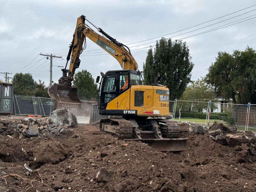 Yellow Demolition Masters excavator on a Melbourne earthworks site with cleared earth